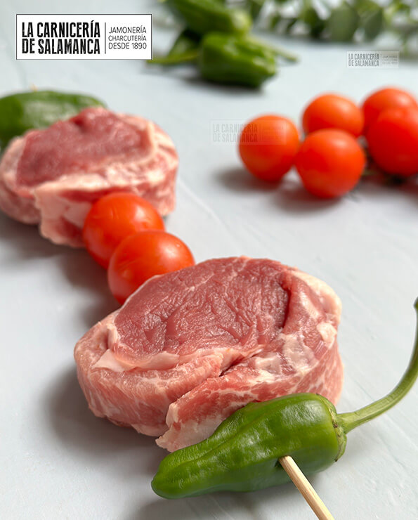 Brocheta de solomillo y secreto ibérico. Además lleva pimientos de padrón y tomates cherry.
