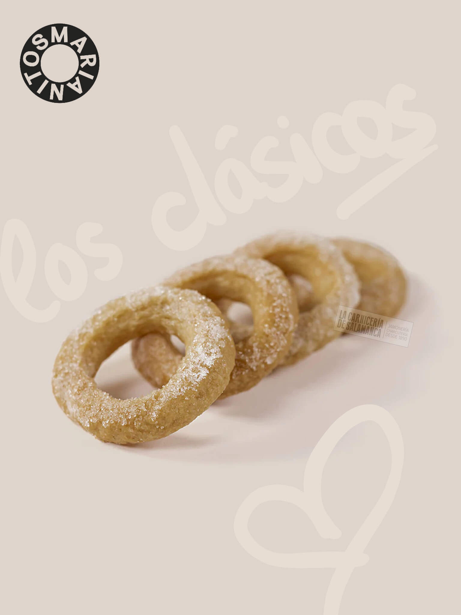 Marianitos clásicos de masa madre artesanal, elaborados con aceite de oliva y un toque de vino blanco. Estos anillos crujientes, espolvoreados con azúcar, ofrecen un sabor auténtico que recuerda a la tradición y a la cocina casera de antaño. Disfruta de la ligereza y la textura crumble & crunchy de estos dulces que son ideales para acompañar tu café, té o como un snack nostálgico. Fondo beige con la frase 