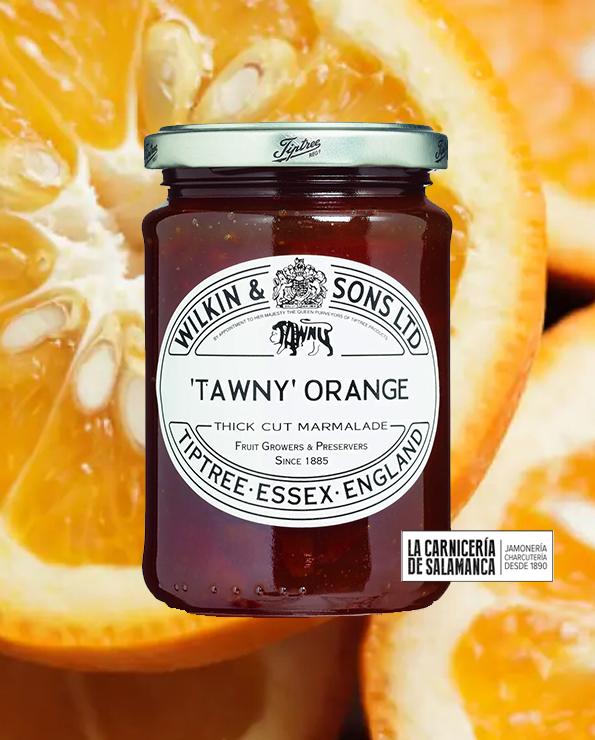 Tarro de mermelada Tawny Orange de Tiptree sobre fondo de naranjas amargas. Producto artesanal con corteza gruesa, disponible en La Carnicería de Salamanca, Peñaranda de Bracamonte.