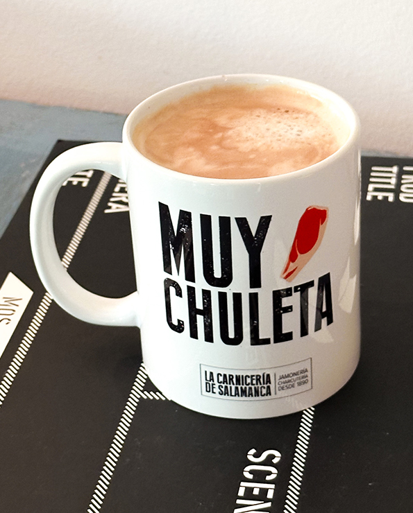 Taza MUY CHULETA de La Carnicería de Salamanca con café caliente, diseño divertido y logo de la carnicería.
